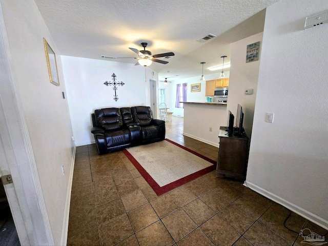 living room featuring a textured ceiling, ceiling fan, and dark tile patterned floors