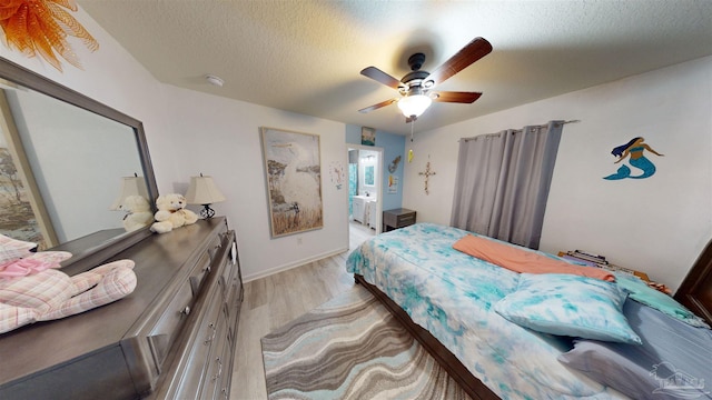 bedroom with a textured ceiling, ceiling fan, and light hardwood / wood-style floors