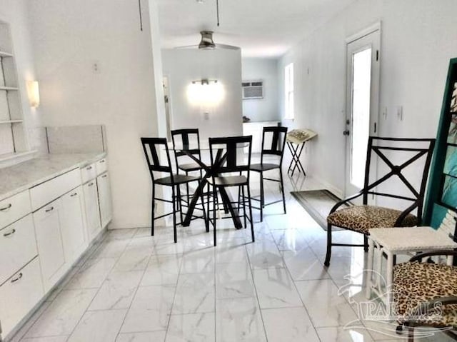 dining area with a ceiling fan, marble finish floor, and a wall unit AC