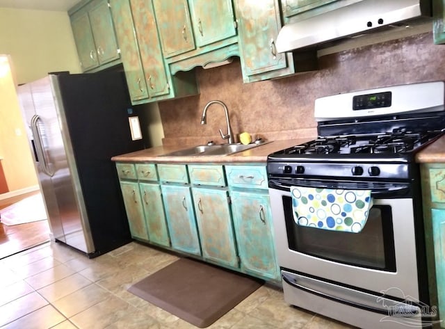 kitchen with appliances with stainless steel finishes, a sink, under cabinet range hood, green cabinets, and backsplash