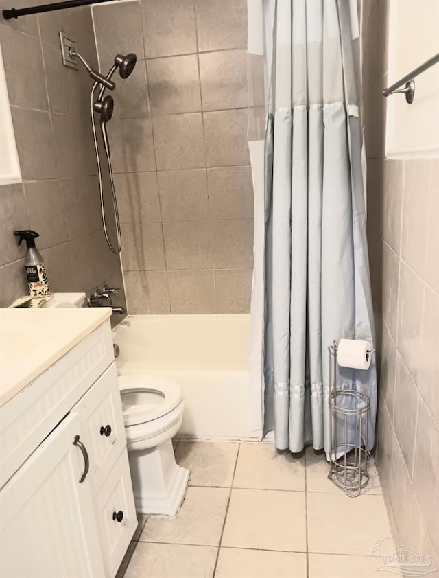 bathroom with toilet, shower / tub combo with curtain, tile patterned floors, vanity, and tile walls