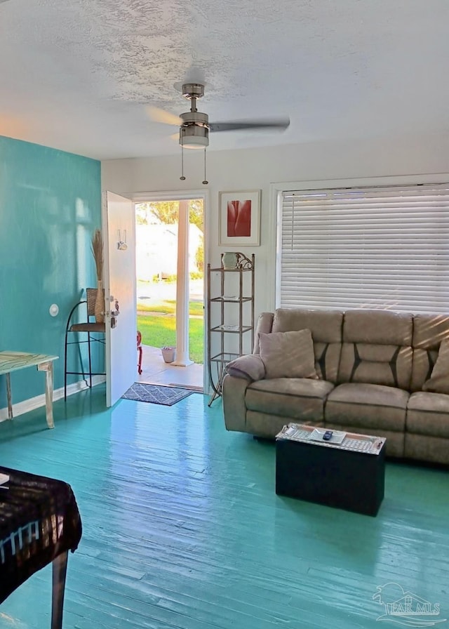 living room with a textured ceiling, ceiling fan, wood finished floors, and baseboards