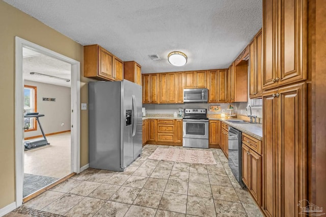2762 Christine St, Pensacola, FL 32526 - kitchen with appliances with stainless steel finishes, a textured ceiling, brown cabinets, and light countertops
