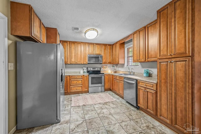2762 Christine St, Pensacola, FL 32526 - kitchen with stainless steel appliances, brown cabinets, a textured ceiling, and light countertops