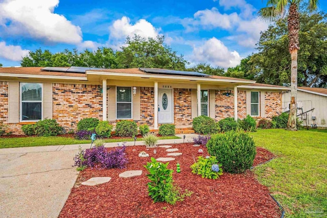 2762 Christine St, Pensacola, FL 32526 - view of front of home featuring brick siding, a front lawn, roof mounted solar panels, and covered porch