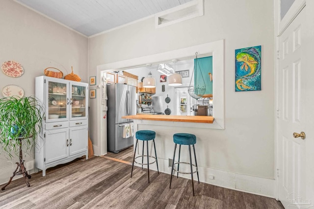 1220 E Cervantes, Pensacola, FL 32501 - kitchen with freestanding refrigerator, wood finished floors, a breakfast bar, glass insert cabinets, and ornamental molding