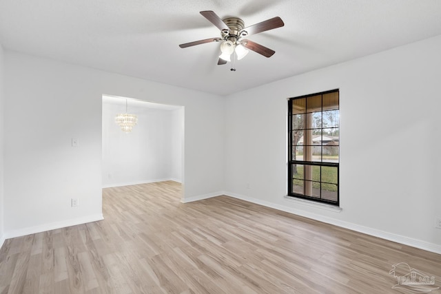 unfurnished room featuring ceiling fan with notable chandelier and light hardwood / wood-style flooring