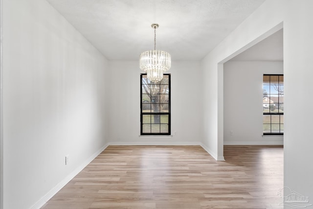 unfurnished dining area with an inviting chandelier and light wood-type flooring