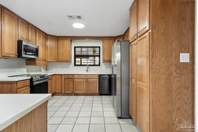 kitchen with appliances with stainless steel finishes, sink, and light tile patterned floors