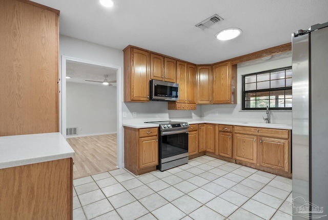 kitchen with sink, stainless steel appliances, ceiling fan, and light tile patterned flooring