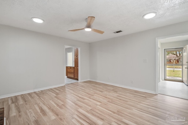 empty room with ceiling fan, light hardwood / wood-style floors, and a textured ceiling