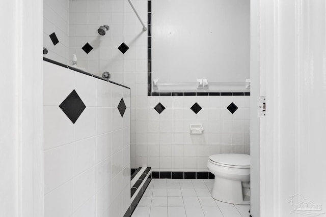 bathroom featuring tile patterned flooring, tile walls, toilet, and tiled shower