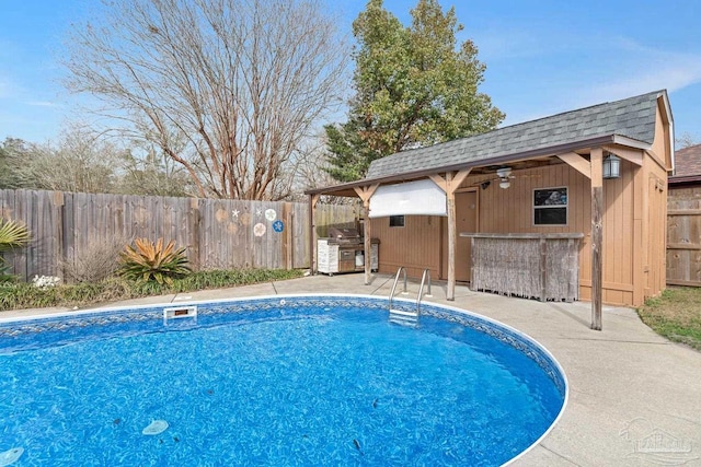 view of swimming pool with an outbuilding, an outdoor kitchen, an outdoor bar, and a patio area