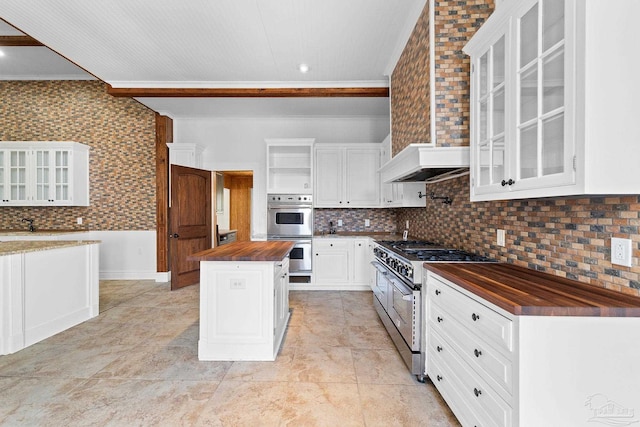 kitchen featuring wood counters, stainless steel appliances, a kitchen island, and white cabinets