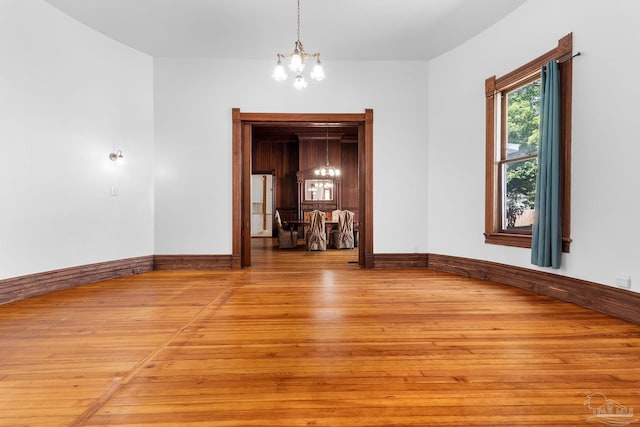 spare room with light hardwood / wood-style floors and a chandelier