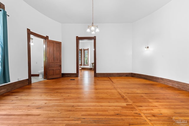 unfurnished room with an inviting chandelier and light wood-type flooring