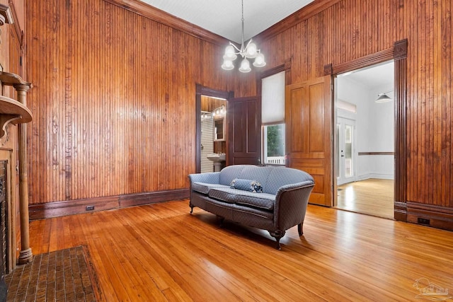 sitting room featuring wood walls, a chandelier, and light wood-type flooring