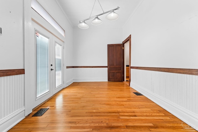 corridor with french doors, crown molding, and light hardwood / wood-style flooring