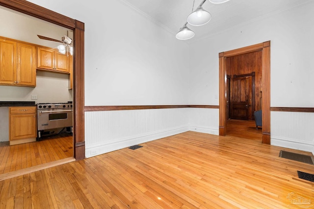 unfurnished dining area featuring crown molding, ceiling fan, and light wood-type flooring