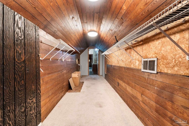 hall featuring carpet, vaulted ceiling, wooden ceiling, and wood walls