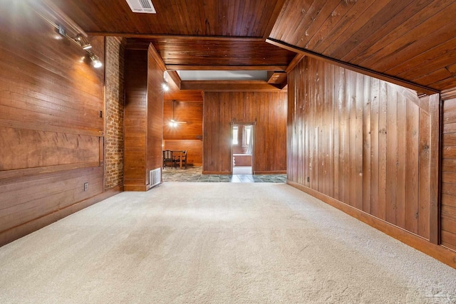 empty room with wood walls, light carpet, and wooden ceiling