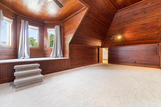 additional living space featuring ceiling fan, light carpet, wood ceiling, and wood walls