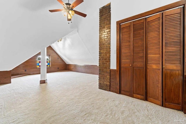 bonus room featuring ceiling fan, light colored carpet, wooden walls, and vaulted ceiling