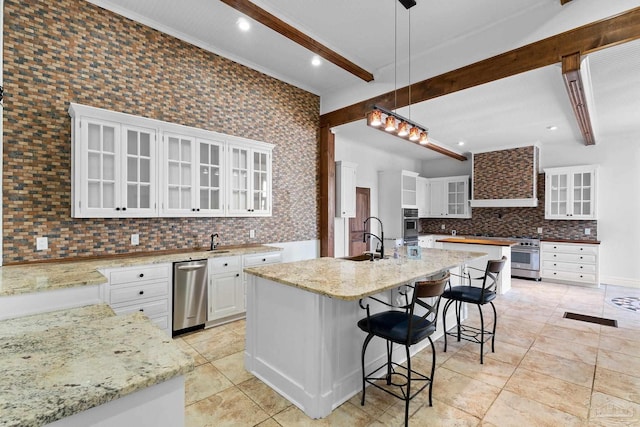 kitchen with pendant lighting, a kitchen island with sink, beam ceiling, white cabinets, and decorative backsplash