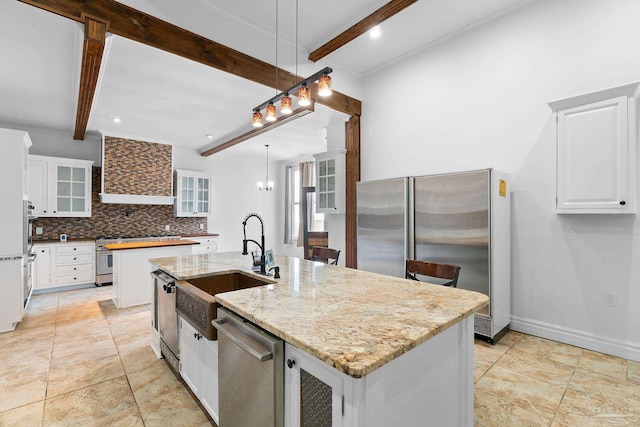 kitchen featuring appliances with stainless steel finishes, decorative light fixtures, white cabinetry, an island with sink, and beam ceiling