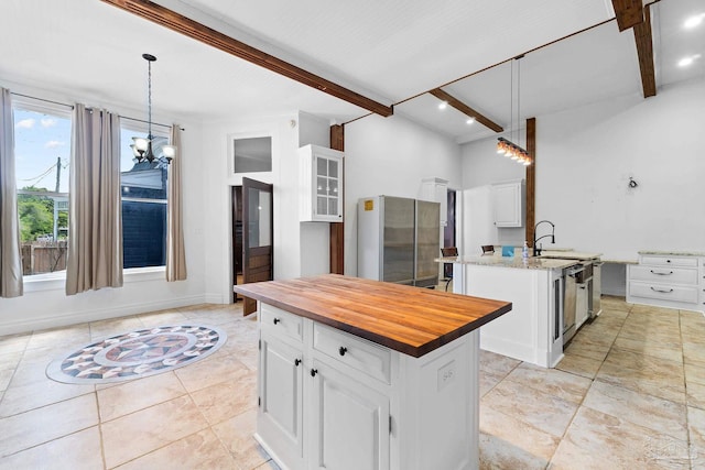 kitchen with pendant lighting, beam ceiling, and a kitchen island with sink