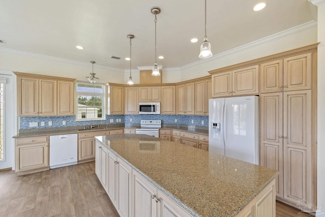 kitchen featuring pendant lighting, sink, a center island, light stone counters, and white appliances