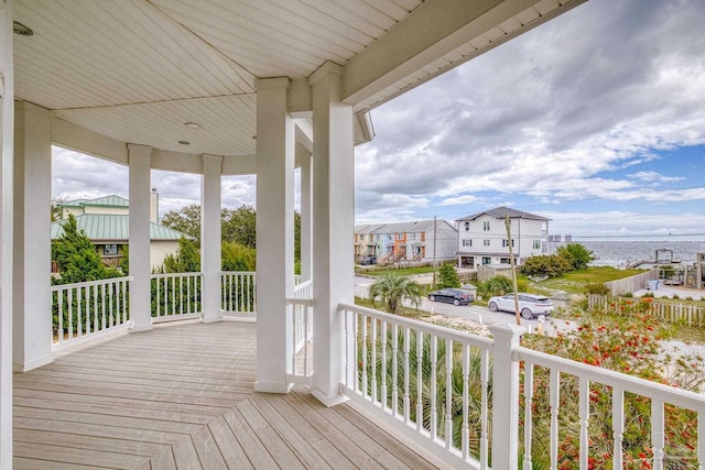 wooden terrace featuring covered porch and a water view