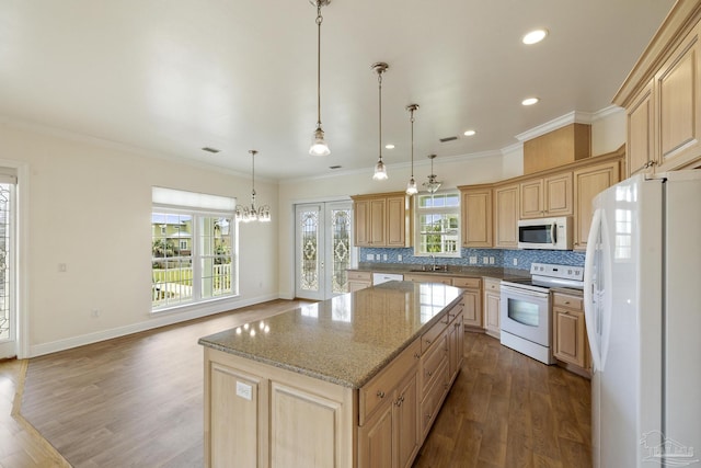 kitchen featuring sink, white appliances, a center island, light stone countertops, and decorative light fixtures