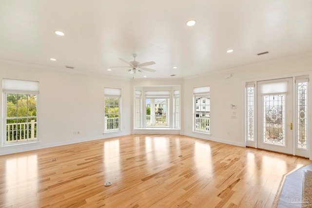 unfurnished living room with light wood-type flooring, crown molding, a wealth of natural light, and ceiling fan