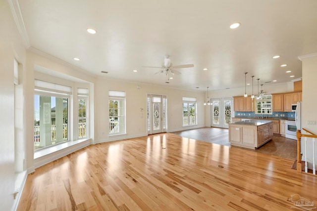 unfurnished living room featuring crown molding, ceiling fan, and light wood-type flooring