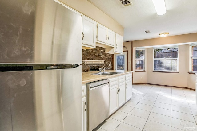 kitchen with light tile patterned flooring, appliances with stainless steel finishes, white cabinetry, and sink