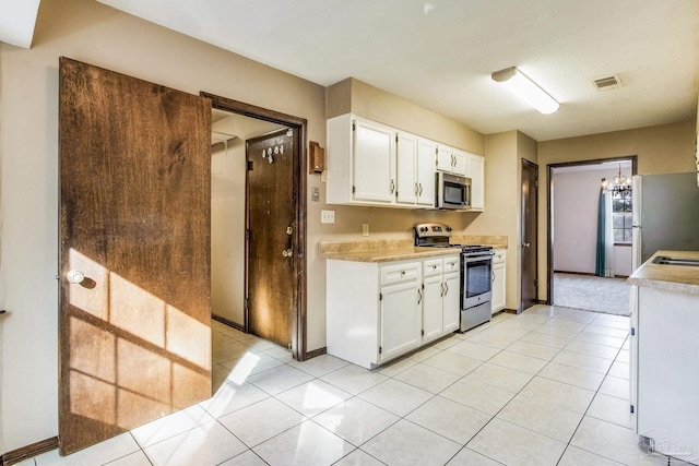 kitchen with light tile patterned floors, stainless steel appliances, and white cabinetry