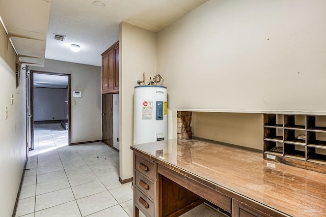 kitchen featuring electric water heater, light tile patterned flooring, and a textured ceiling