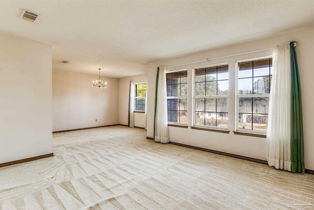 unfurnished room featuring a chandelier, a textured ceiling, and light colored carpet