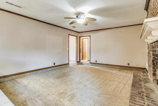 unfurnished room featuring ceiling fan, crown molding, carpet floors, and a fireplace