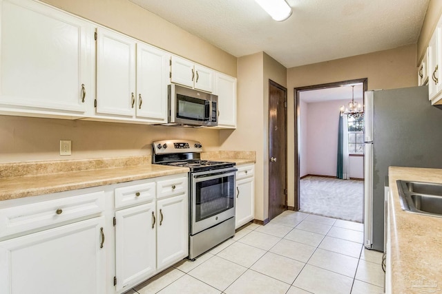 kitchen featuring white cabinets, pendant lighting, a notable chandelier, and appliances with stainless steel finishes