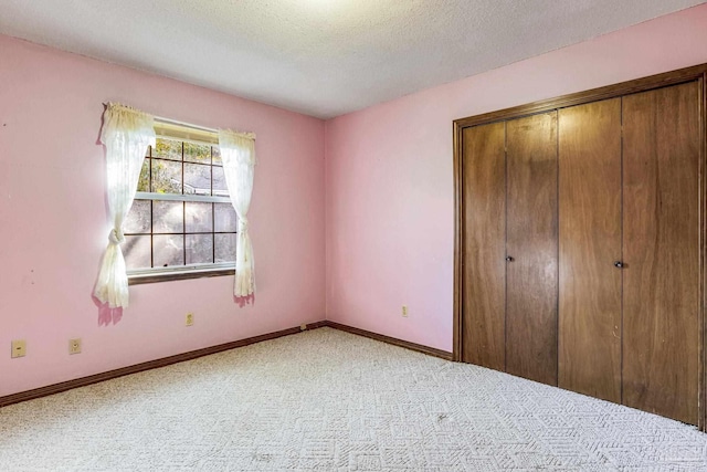 unfurnished bedroom featuring a textured ceiling, light carpet, and a closet