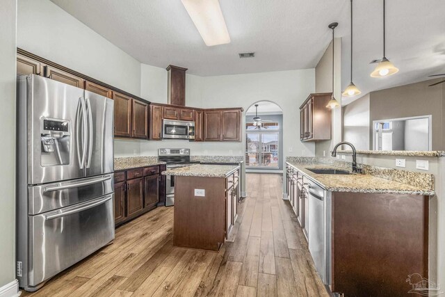 kitchen with sink, dark brown cabinets, stainless steel appliances, and a center island