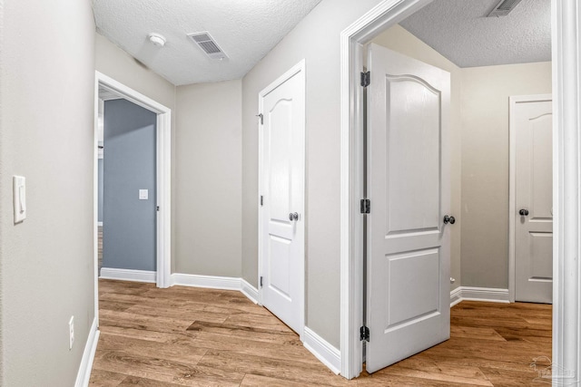 hallway with hardwood / wood-style floors and a textured ceiling