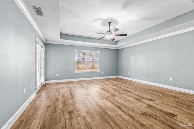 unfurnished room featuring ceiling fan, a raised ceiling, crown molding, a textured ceiling, and light hardwood / wood-style flooring