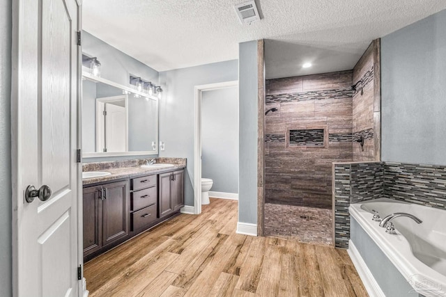 full bathroom featuring hardwood / wood-style floors, vanity, a textured ceiling, shower with separate bathtub, and toilet