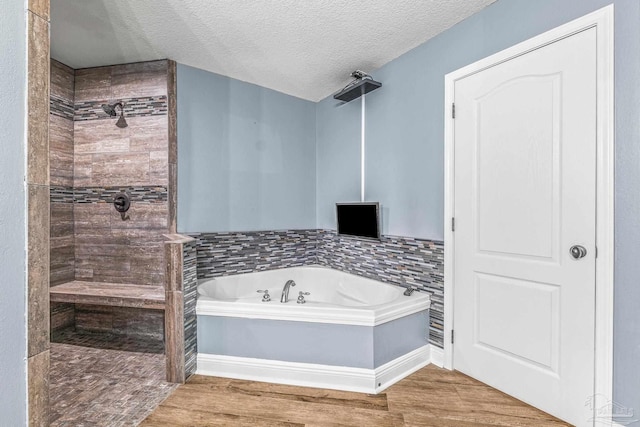 bathroom featuring wood-type flooring, shower with separate bathtub, and a textured ceiling