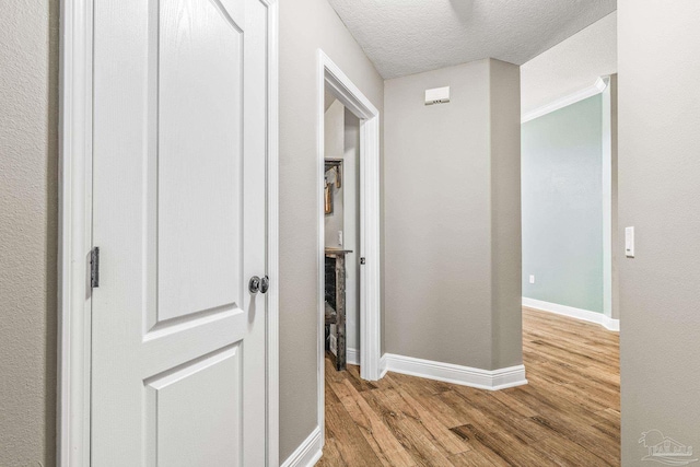 hallway featuring a textured ceiling and light hardwood / wood-style floors