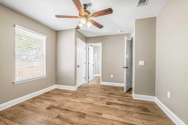 empty room featuring ceiling fan, a textured ceiling, and light wood-type flooring