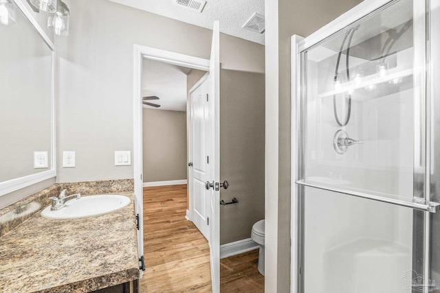 bathroom with wood-type flooring, vanity, an enclosed shower, toilet, and a textured ceiling